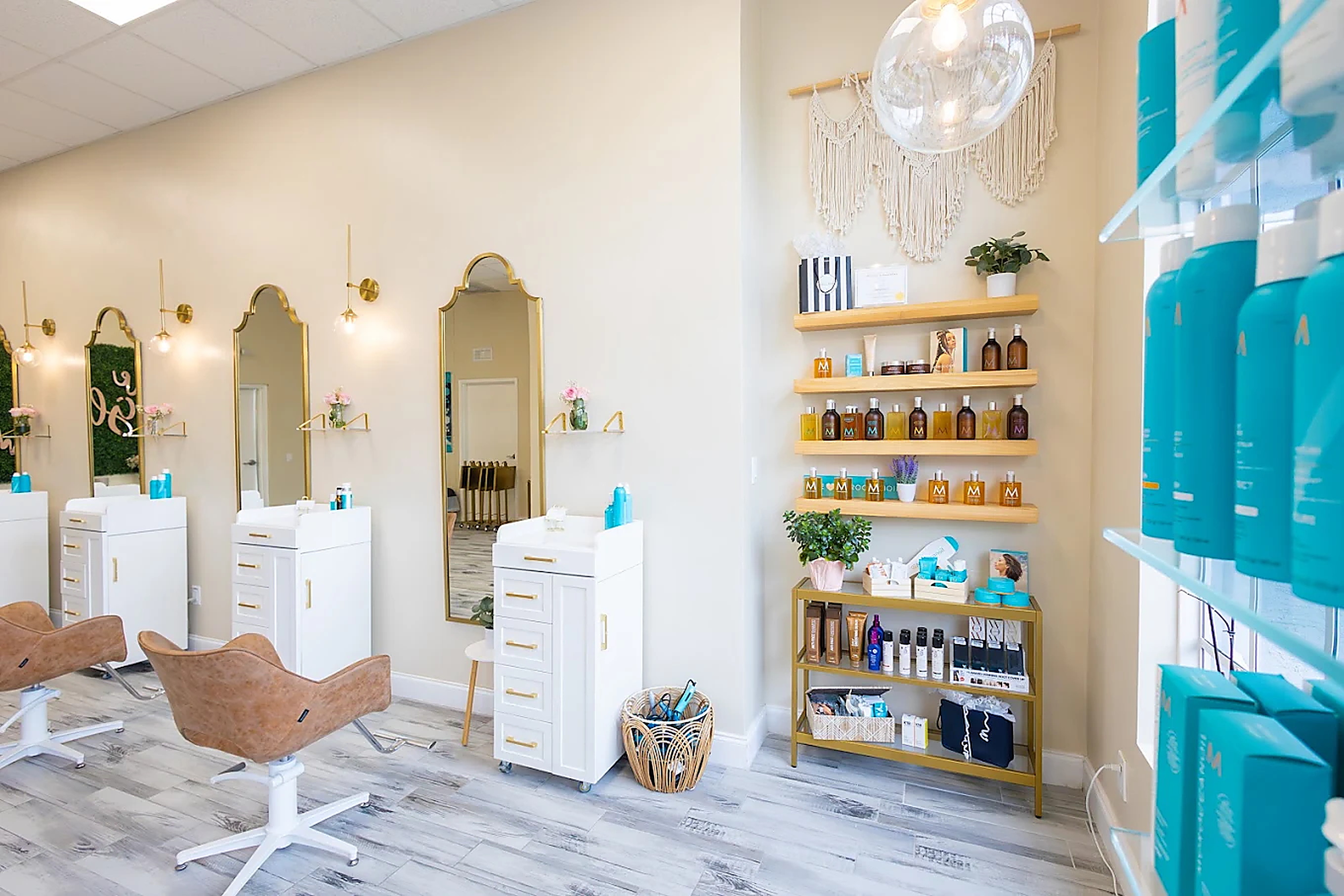 The Glam Room salon floor with white styling stations and gold-framed mirrors