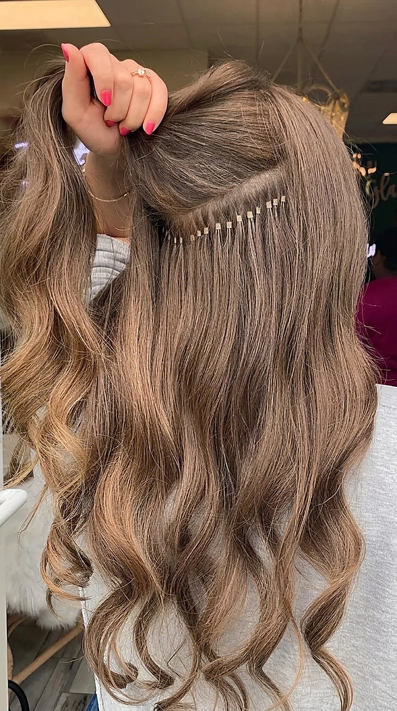 Close-up of K-tip hair extensions being applied to brown hair